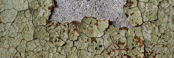 Peeling paint on the wall. Panorama of a concrete wall with old cracked flaking paint. Weathered rough painted surface with patterns of cracks and peeling. Wide panoramic texture for grunge background