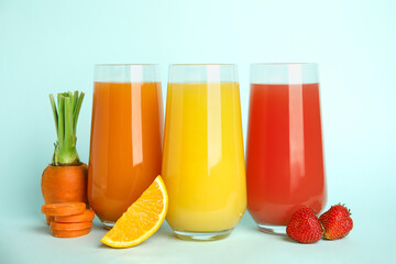 Glasses of delicious juices and fresh ingredients on light blue background