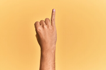 Arm and hand of caucasian man over yellow isolated background showing little finger as pinky promise commitment, number one