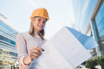 Professional architect holding blueprints outdoors.