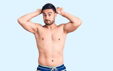 Fototapeta premium Young handsome man wearing swimwear doing bunny ears gesture with hands palms looking cynical and skeptical. easter rabbit concept.