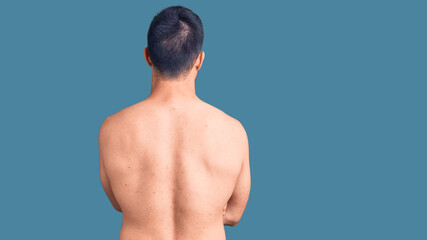 Young handsome man wearing swimwear standing backwards looking away with crossed arms