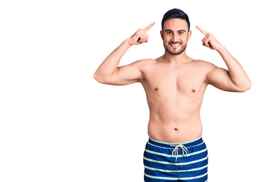 Young handsome man wearing swimwear smiling pointing to head with both hands finger, great idea or thought, good memory