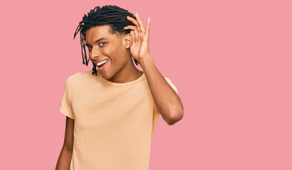 Fototapeta premium Young african american man wearing casual clothes smiling with hand over ear listening an hearing to rumor or gossip. deafness concept.