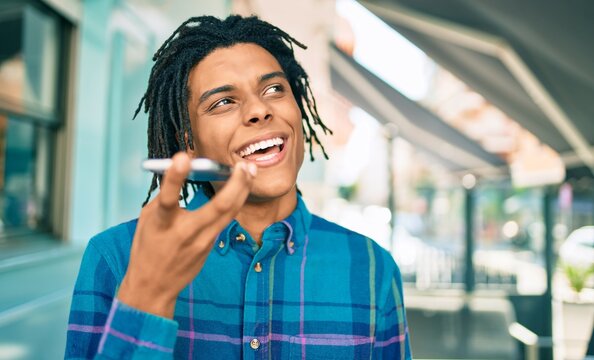 Young african american man sending audio message using smartphone at street of city.