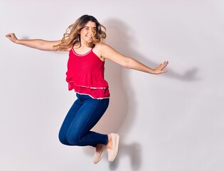 Young beautiful caucasian woman wearing casual clothes smiling happy. Jumping with smile on face and arms opened over isolated white background