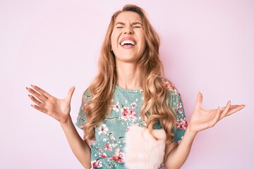 Young caucasian woman with blond hair wearing casual clothes celebrating mad and crazy for success...