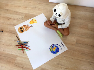 a child sits on the floor and thinks about a wall paper for school with an owl and a globe in pencil