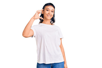 Young woman wearing casual clothes smiling and confident gesturing with hand doing small size sign with fingers looking and the camera. measure concept.