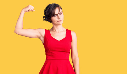 Beautiful young woman with short hair wearing casual style with sleeveless shirt strong person...