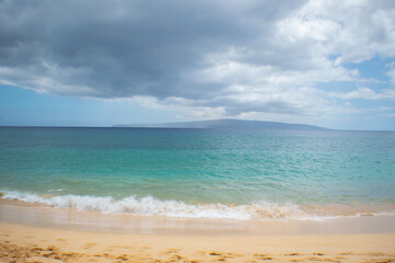 Fototapeta na wymiar Beach in Hawaii with a dark cloud passing above.