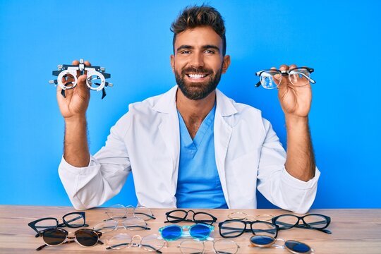 Young hispanic man with optometry glasses sitting at the table smiling with a happy and cool smile on face. showing teeth.