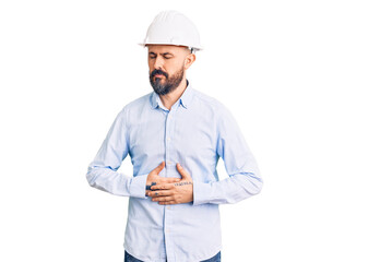 Young handsome man wearing architect hardhat with hand on stomach because indigestion, painful illness feeling unwell. ache concept.