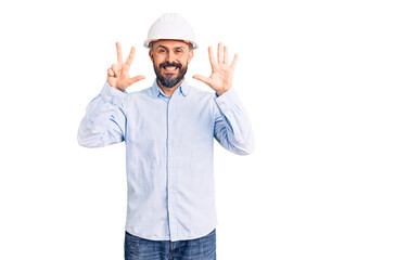 Young handsome man wearing architect hardhat showing and pointing up with fingers number eight while smiling confident and happy.