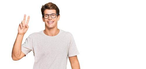 Handsome caucasian man wearing casual clothes and glasses smiling looking to the camera showing fingers doing victory sign. number two.