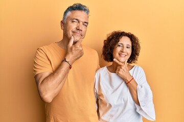 Beautiful middle age couple together wearing casual clothes looking confident at the camera smiling with crossed arms and hand raised on chin. thinking positive.
