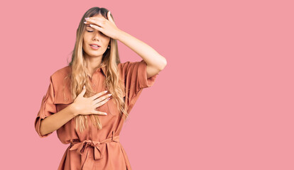 Fototapeta premium Beautiful caucasian woman with blonde hair wearing summer jumpsuit touching forehead for illness and fever, flu and cold, virus sick