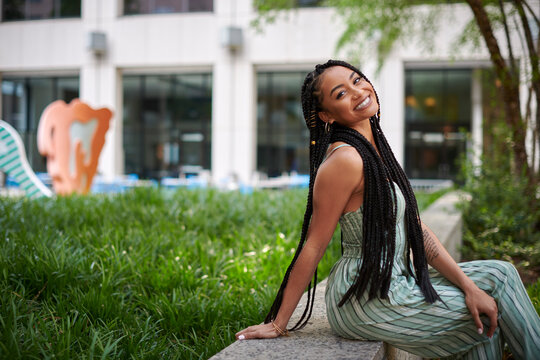 Stunning young biracial woman stands on city street in summer - wearing green striped romper