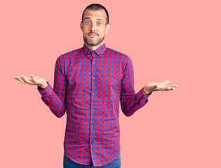 Young handsome man wearing casual clothes clueless and confused expression with arms and hands...