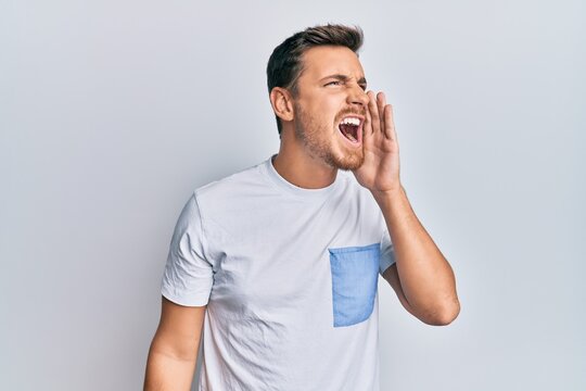 Handsome caucasian man wearing casual clothes shouting and screaming loud to side with hand on mouth. communication concept.