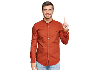 Handsome caucasian man wearing casual clothes showing and pointing up with finger number one while smiling confident and happy.