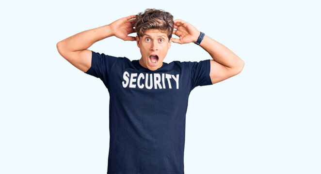 Young handsome man wearing security t shirt crazy and scared with hands on head, afraid and surprised of shock with open mouth