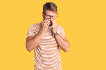 Young caucasian man wearing casual clothes and glasses rubbing eyes for fatigue and headache,...