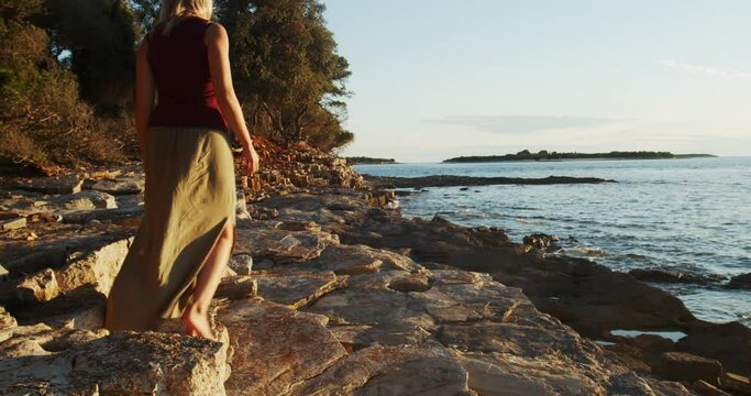 Woman walking barefoot on the rocky coast of Brijuni National Park, Adriatic Sea, Croatia