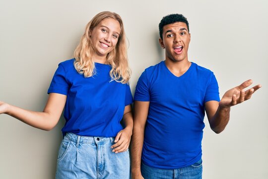 Young interracial couple wearing casual clothes smiling cheerful offering hands giving assistance and acceptance.