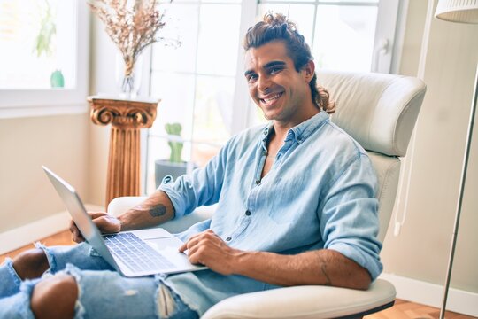 Young hispanic man smiling happy using laptop at home