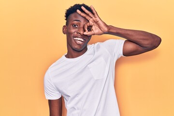 Fototapeta na wymiar Young african american man wearing casual clothes doing ok gesture with hand smiling, eye looking through fingers with happy face.