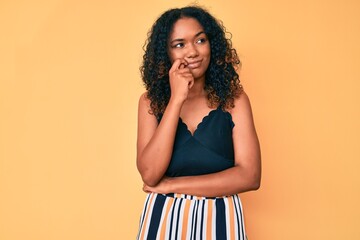 Young african american woman wearing casual clothes thinking concentrated about doubt with finger on chin and looking up wondering