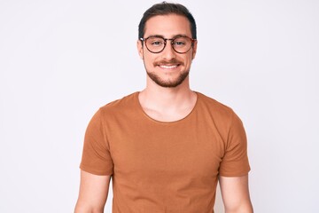 Young handsome man wearing casual clothes and glasses looking positive and happy standing and smiling with a confident smile showing teeth