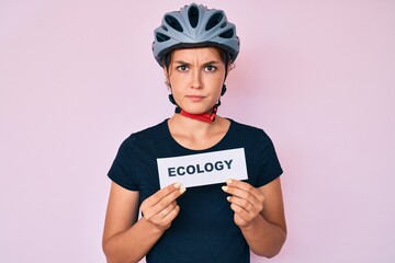 Beautiful caucasian woman wearing bike helmet holding ecology word skeptic and nervous, frowning upset because of problem. negative person.