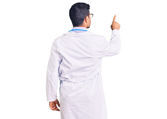 Young hispanic man wearing doctor uniform and stethoscope posing backwards pointing ahead with...
