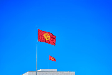 Two Kyrgyzstan flags waving in the wind against blue sky together. Diplomacy concept, international relations, patriotism. Symbol of the state.
