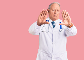 Senior handsome grey-haired man wearing doctor coat and stethoscope doing frame using hands palms...