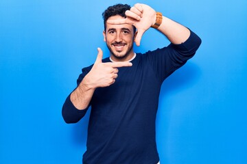 Naklejka premium Young hispanic man wearing casual clothes smiling making frame with hands and fingers with happy face. creativity and photography concept.