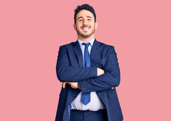 Young hispanic man wearing business clothes happy face smiling with crossed arms looking at the camera. positive person.
