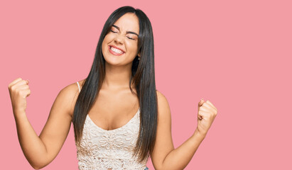 Young beautiful hispanic girl wearing casual clothes very happy and excited doing winner gesture with arms raised, smiling and screaming for success. celebration concept.