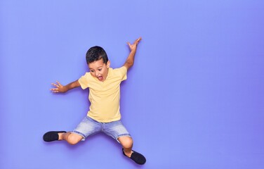 Fototapeta na wymiar Adorable kid wearing casual clothes jumping over isolated purple background