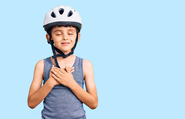 Little cute boy kid wearing bike helmet smiling with hands on chest with closed eyes and grateful gesture on face. health concept.