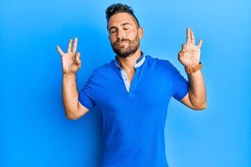 Handsome man with beard wearing casual clothes relax and smiling with eyes closed doing meditation gesture with fingers. yoga concept.