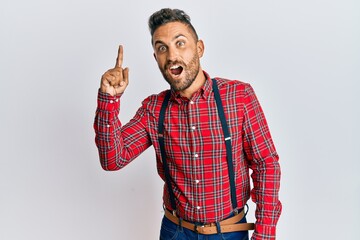 Naklejka premium Handsome man with beard wearing hipster elegant look pointing finger up with successful idea. exited and happy. number one.
