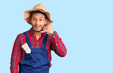 Handsome latin american young man weaing handyman uniform smiling doing phone gesture with hand and fingers like talking on the telephone. communicating concepts.