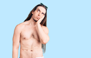 Naklejka premium Young adult man with long hair wearing swimwear shirtless thinking looking tired and bored with depression problems with crossed arms.