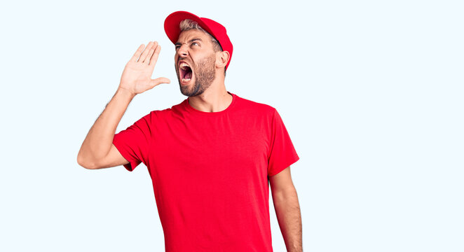 Young handsome blond man wearing t-shirt and cap shouting and screaming loud to side with hand on mouth. communication concept.