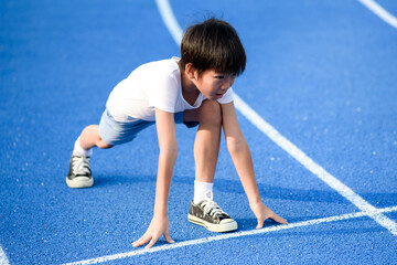 Young boy running on blue track