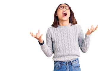 Young beautiful chinese girl wearing casual clothes crazy and mad shouting and yelling with aggressive expression and arms raised. frustration concept.