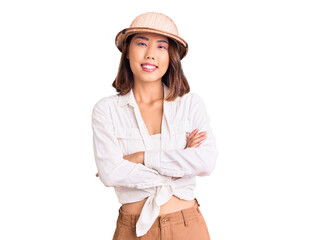 Young beautiful chinese girl wearing explorer hat happy face smiling with crossed arms looking at the camera. positive person.